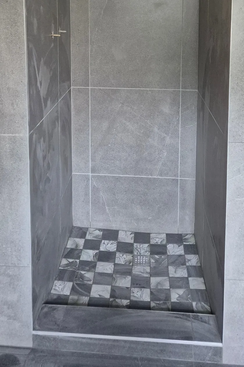 After: the shower retiled in large grey tiles, with a chequered mosaic floor