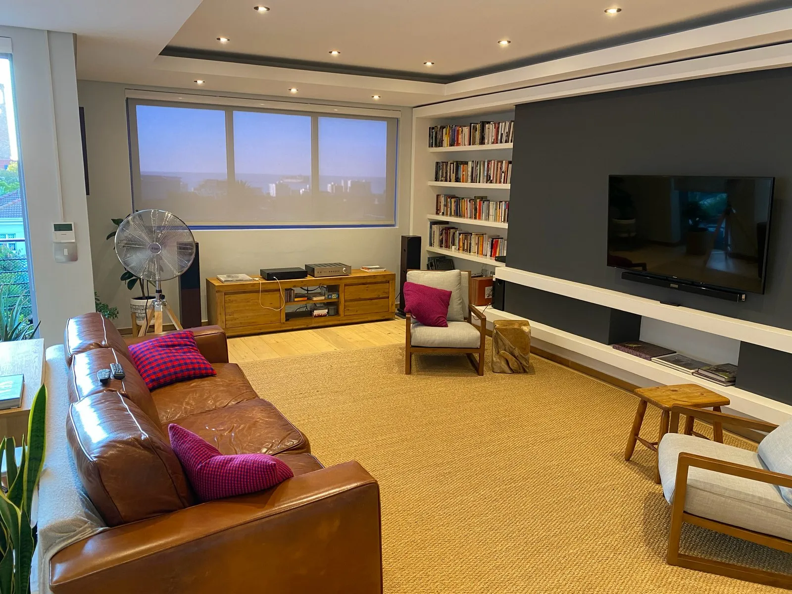 Living room of the Green Point apartment, with the sea beyond the window blind