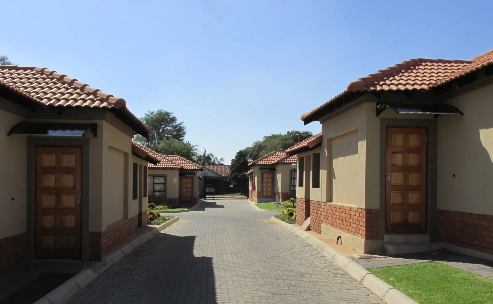 Single-storey units with tiled roofs and timber front doors either side of a paved road